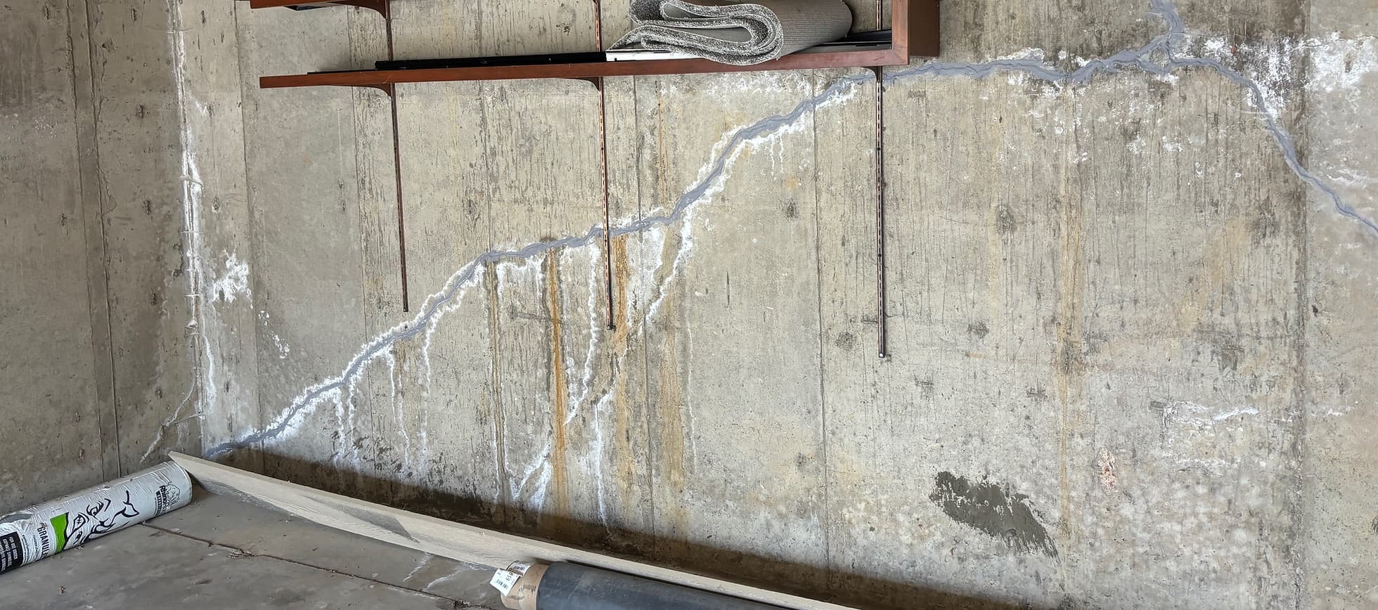 Long diagonal crack in a poured basement wall, sealed with grey epoxy