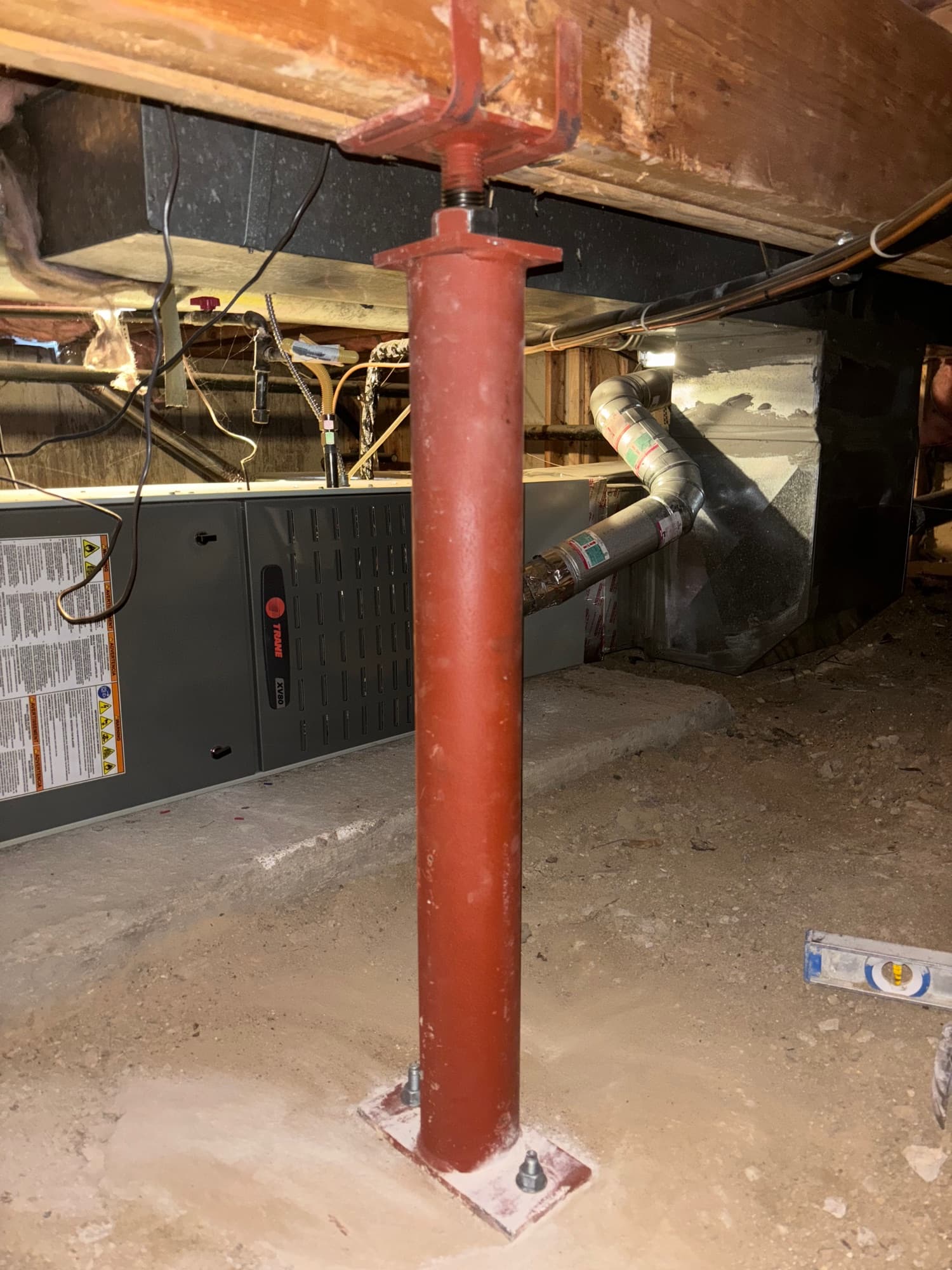 Red steel support post bolted to a plate, holding up a crawl space beam